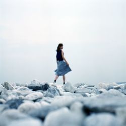 Surface level of woman walking on pebble beach