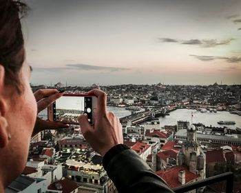 Man photographing cityscape against sky