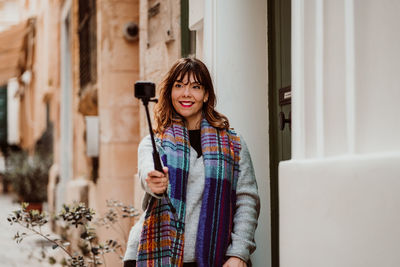 Woman holding monopod standing in alley