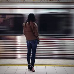 Rear view of woman standing in subway train