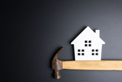 Directly above shot of model home and hammer over black background