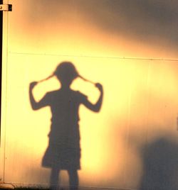 Shadow of girl playing with hair on metallic door