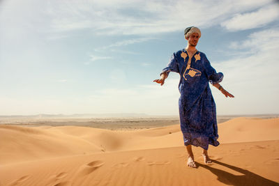 Man standing on sand against sky at desert