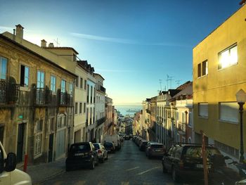 Cars on road in city against blue sky