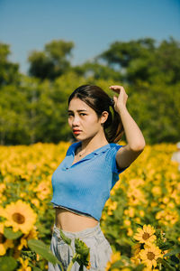Young woman standing against sunflowers