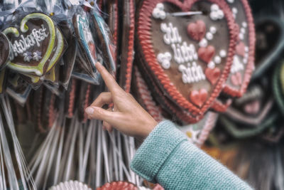 Cropped hand of woman pointing on decoration hanging at market stall