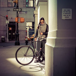 Young woman with bicycle standing in city