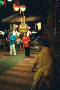 Side view of man standing on street at night