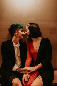 Young romantic stylish ladies having a romantic moment together while sitting on a bench