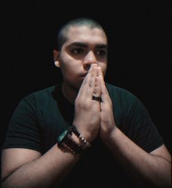 Portrait of young man making face against black background