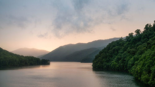 Scenic view of river by mountains against sky