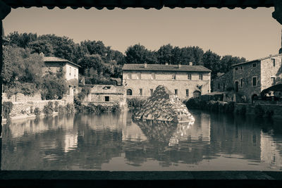 Scenic view of lake by buildings against sky