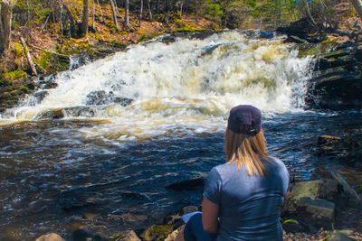 Rear view of man looking at waterfall