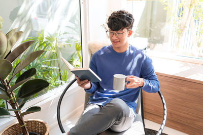 Young woman using laptop while sitting on sofa at home