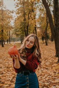 Portrait of smiling young woman holding autumn leaves