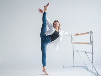 Smiling woman with leg up against white background