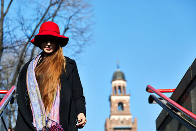 Woman wearing hat standing against sky in city