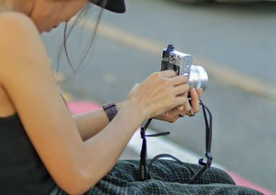 Midsection of woman photographing while sitting outdoors