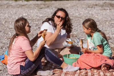 Single mother with her two little daughters, eating at a rest stop during a hike