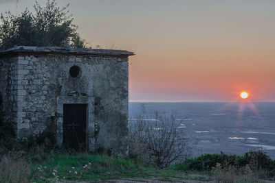 Old building on field against sky during sunset