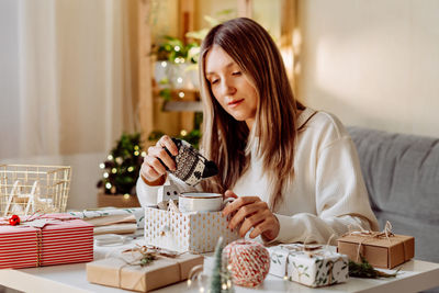 Woman touching christmas gift while having coffee