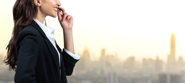 Side view of young woman standing against blurred background