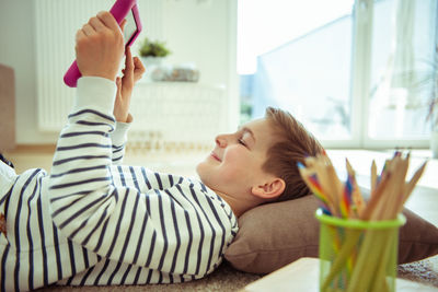 Portrait of smiling boy lying on sofa at home