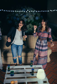 Cheerful female friends having party at patio during night