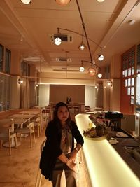 Portrait of woman sitting in illuminated restaurant 