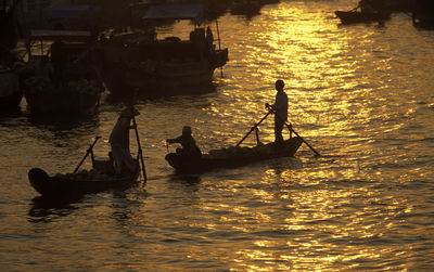 High angle view of people rowing boats in river during sunset