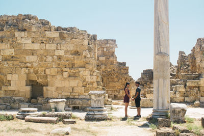 Side view of couple looking at each other while standing at old ruin