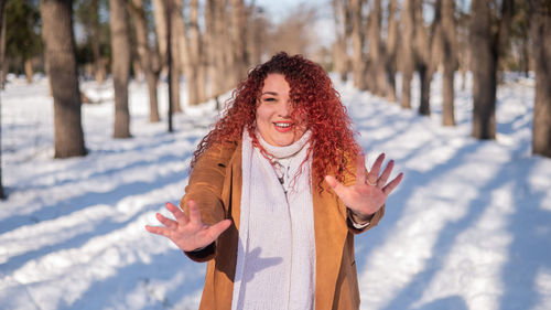 Portrait of young woman standing on snow covered field