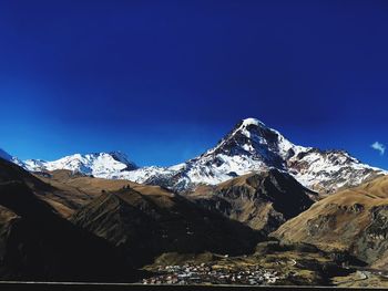 Scenic view of snowcapped mountains against clear blue sky