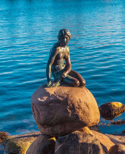 Stack of man sitting on rock by lake