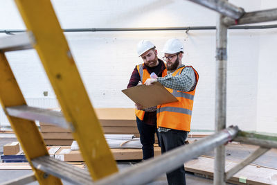 Engineers wearing hardhat having discussion over document