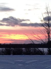 Scenic view of snow covered landscape against sky at sunset