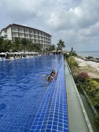 Man swimming in pool by building against sky