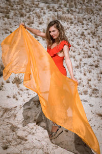 High angle portrait of young woman holding scarf standing on land