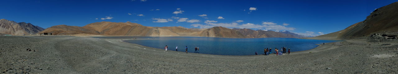 Panoramic view of beach and mountains against blue sky