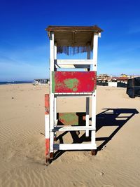 Lifeguard hut on beach against blue sky