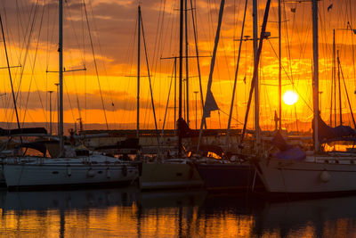 Sailboats moored at harbor during sunset