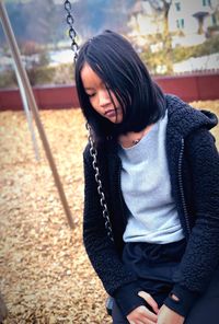 Young woman sitting on swing at park