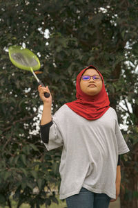 Portrait of young woman standing against plants