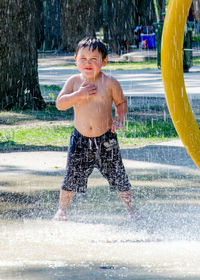 Wet little boy cools off in an outdoor fountain on a hot summers day