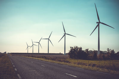 Wind turbines on field against sky