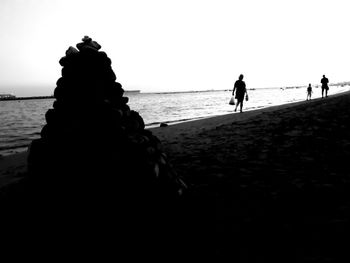 Silhouette people on beach against clear sky