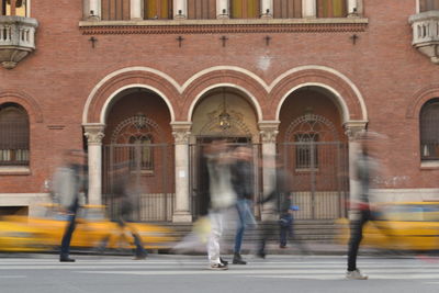 People walking on street against buildings in city