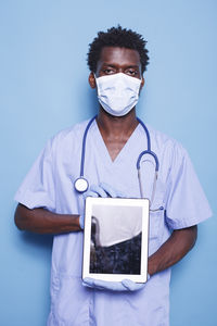 Midsection of doctor holding clipboard against blue background