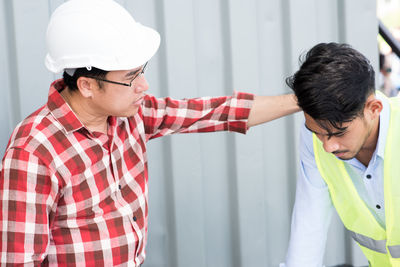 Architect explaining to coworker against corrugated iron