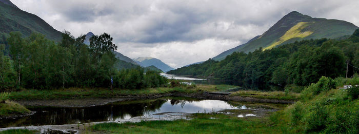 Scenic view of mountains and lake against cloudy sky